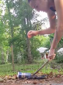 Woman rescues a snake trapped in a beer can at the side of a road