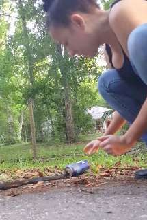 Woman rescues a snake trapped in a beer can at the side of a road