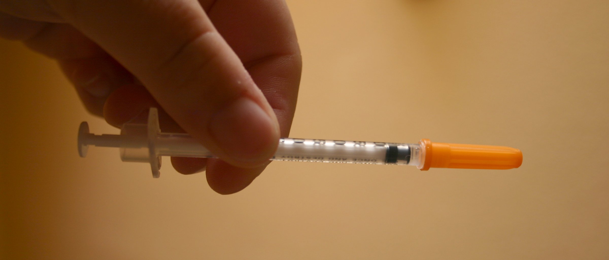 A hand holding a small insulin syringe measured out for a cat