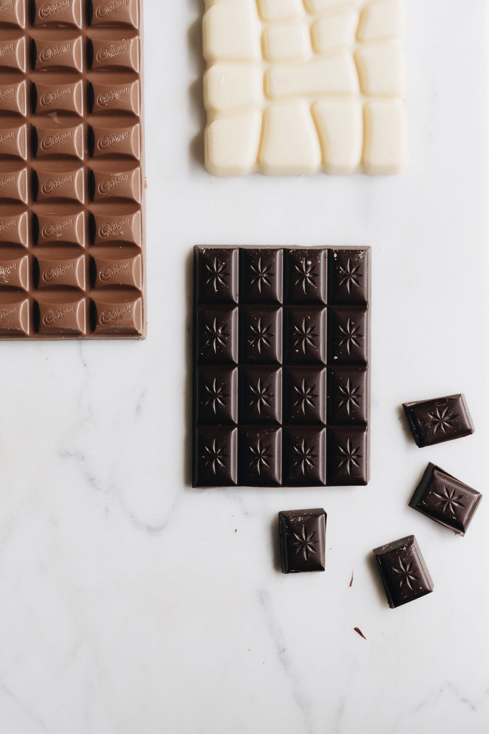 Assorted dark, milk and white chocolate bars on marble – the darker the chocolate, the more toxic it is to dogs