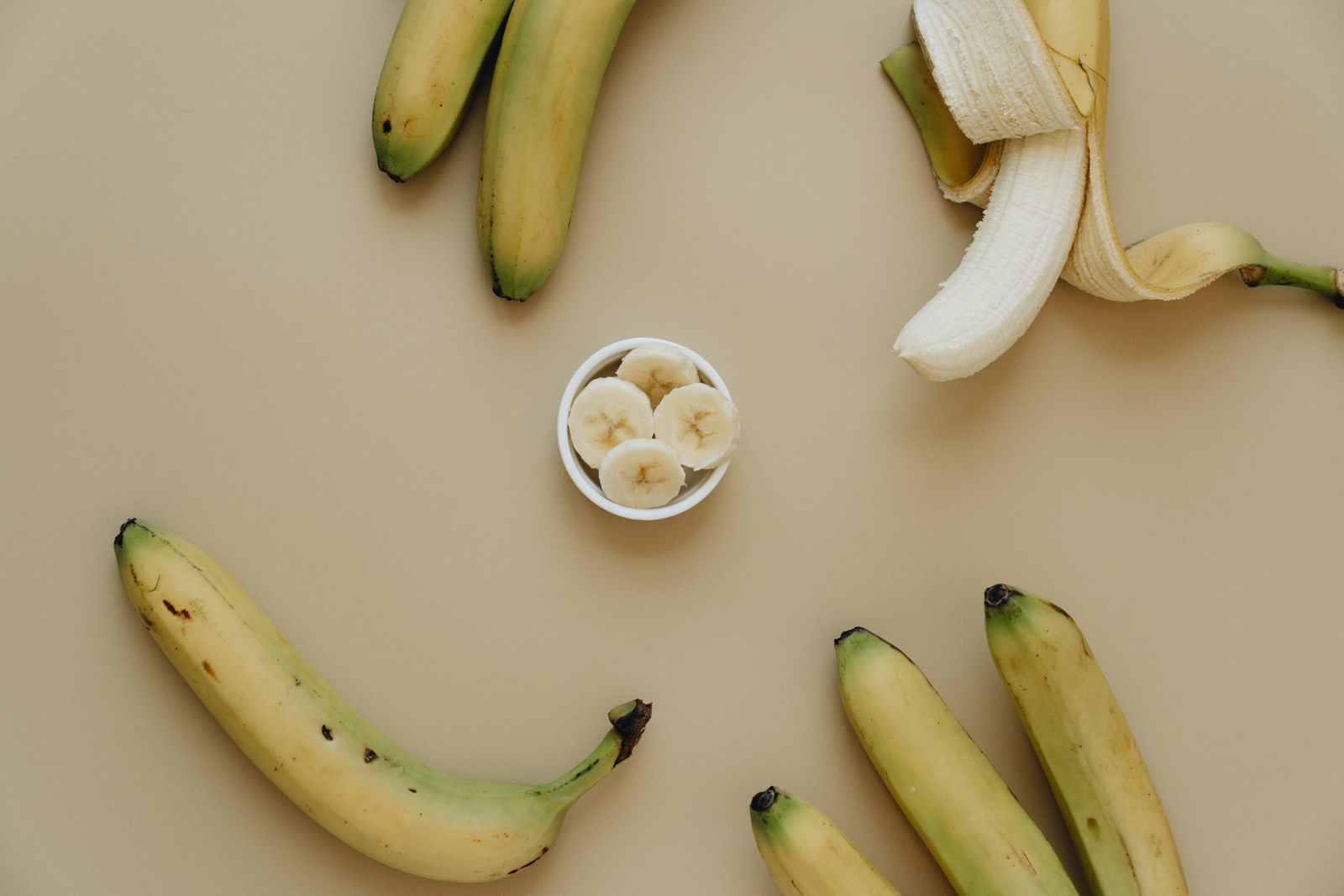 Whole and sliced bananas on a neutral background – banana slices make a safe dog treat