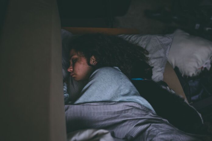 Why does my cat sleep on me – woman asleep with her cat Woman sleeping peacefully in bed with her cat curled up beside her – why does my cat sleep on me